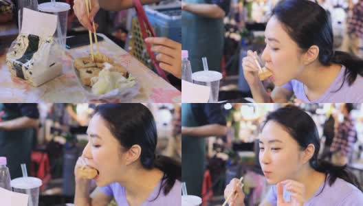 年轻女子在夜市吃臭豆腐高清在线视频素材下载
