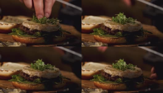 男性的手把绿色的微绿色芥末放在自制汉堡奶酪酱，食物色情的概念。资料片。准备肥美的汉堡高清在线视频素材下载