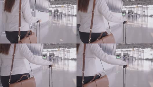 亚洲女商人的手拿行李和肩袋在机场，去做生意，在国外工作，跟随运动手持式后视镜高清在线视频素材下载