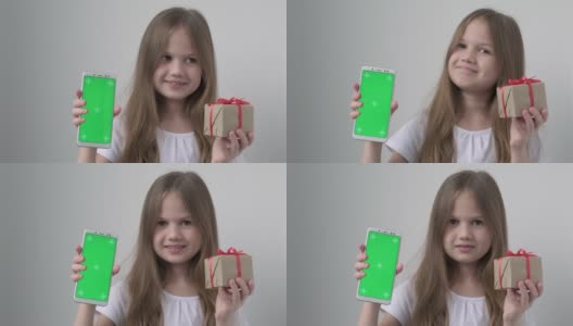可爱的小女孩用绿色屏幕展示手机模拟手机、手机、电话和礼物。绿屏智能手机的色度键设置为广告。圣诞节，情人节，爱，母亲节高清在线视频素材下载