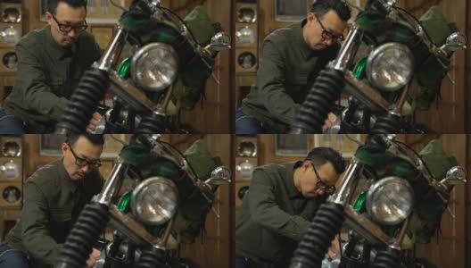 一个男人在他的车库里打磨和维护他的定制摩托车高清在线视频素材下载