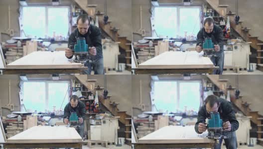 这位65岁的老师傅正在用电动手铣床工作。木工上的小家具厂。高清在线视频素材下载