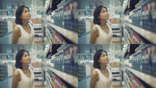 年轻的亚洲女士在超市选择酒精饮料高清在线视频素材下载