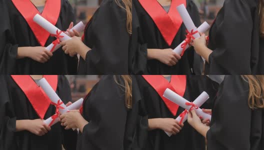 女毕业生手中拿着毕业证书，系着红丝带，谈笑风生高清在线视频素材下载