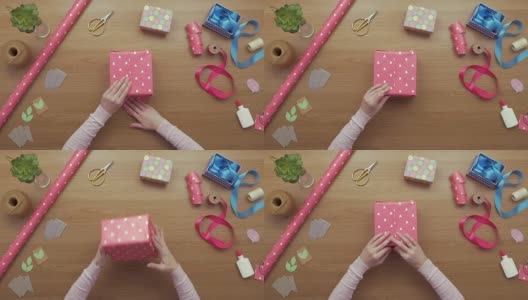 空中拍摄的女子用粉红色包装纸包装礼物的画面高清在线视频素材下载