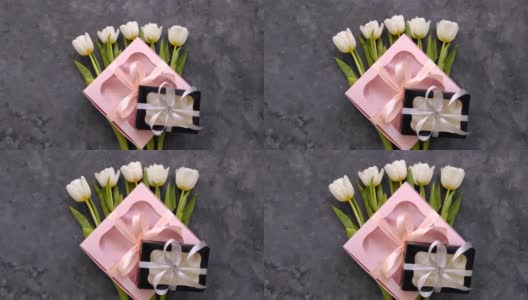 白色郁金香花与黑色和粉红色的礼盒在黑暗的背景平躺。4K视频俯视图。三月八日妇女节快乐的概念。花束，丝带蝴蝶结礼物，女性博客高清在线视频素材下载