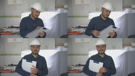 拉丁美洲的承包商在一个房屋项目中改造厨房，在剪贴板上做笔记，然后对着镜头微笑高清在线视频素材下载