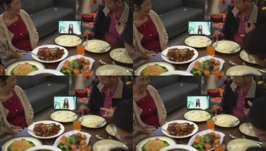 快乐的亚洲华人家庭在团圆饭期间用数码平板电脑视频给亲戚打电话高清在线视频素材下载