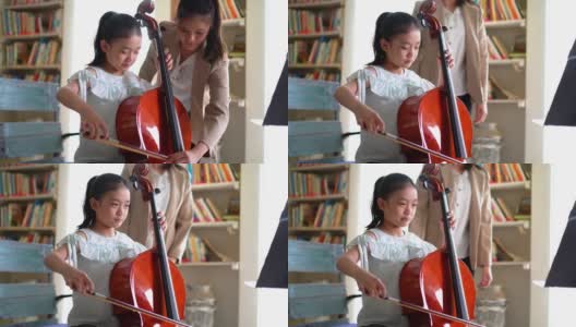 年轻的亚洲女孩学习拉大提琴高清在线视频素材下载