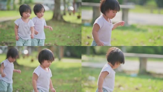 周末早上，一对亚洲华人双胞胎男婴在公园草坪上散步高清在线视频素材下载