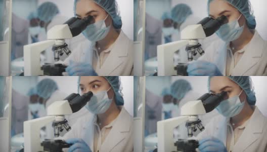 多元化的团队在现代化的实验室中工作。亚洲科学家使用显微镜。穿着防护工作服高清在线视频素材下载