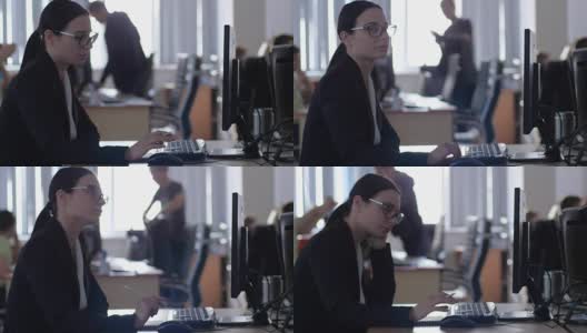 压力管理，疲惫的女商人戴着眼镜，手持铅笔，坐在办公室的办公桌上用电脑工作高清在线视频素材下载