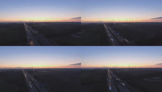 晨光越过农村公路交通，风力涡轮机，从鸟瞰的视角高清在线视频素材下载