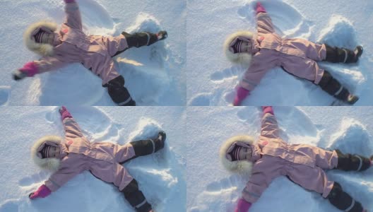 在一个寒冷晴朗的日子里，小女孩躺在雪地里做了一个雪天使高清在线视频素材下载