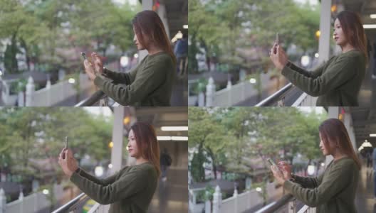 亚洲女性在城市中行走，用智能手机自拍或录像高清在线视频素材下载