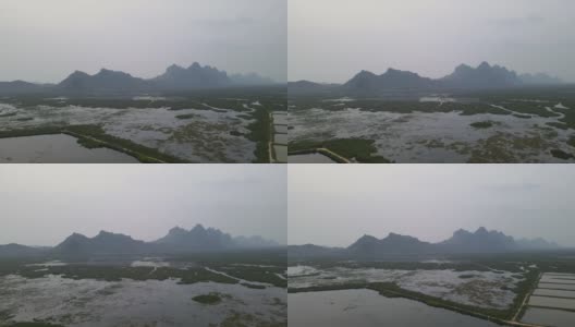 无人机俯视图，在有雾或薄雾的清晨，飞越水田和泥地，向山的方向飞行高清在线视频素材下载
