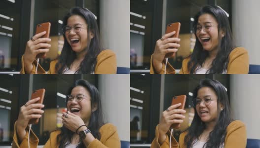 美丽的亚洲年轻女子用她的智能手机视频打电话给朋友或家人，与欢笑快乐的笑脸表情。高清在线视频素材下载