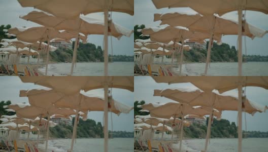 海边有风的天气。空旷的海滩和摇晃的遮阳伞，希腊高清在线视频素材下载