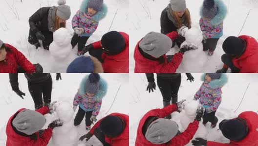 一家人带着孩子在公园里堆雪人。高清在线视频素材下载