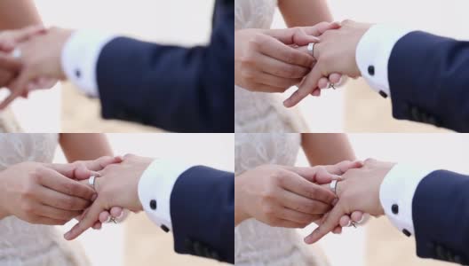 在海滩婚礼上，新娘把结婚戒指戴在新郎的手指上。高清在线视频素材下载