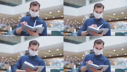 特写。一个戴着防护面具的男人在咖啡馆里看书高清在线视频素材下载