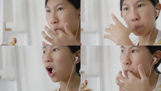 亚洲女孩一边吃着火腿烤面包一边舔手指，一边用智能手机看电影，这是一种生活方式。高清在线视频素材下载