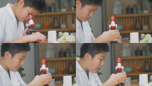 亚洲男孩穿着实验服，在学校实验室使用显微镜进行测试，教育的生活方式理念。高清在线视频素材下载