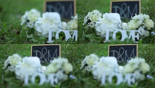 婚礼装饰字爱，鲜花和木质牌匾与字母D和M在公园的绿草背景高清在线视频素材下载