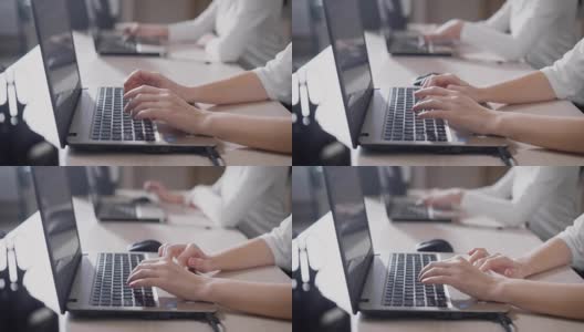 这张照片拍摄的是一位正在用笔记本电脑快速打印文本的女士的手，这两位女士正坐在办公室里的一个便携式设备后面工作高清在线视频素材下载
