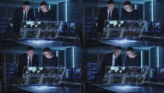 男女政府人员在满是电脑和动画屏幕的大监控室使用触屏互动3D面板。高清在线视频素材下载
