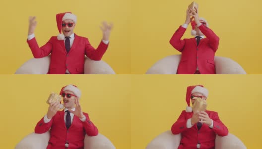 年轻的八字胡电视推销员穿着红色的衣服，戴着圣诞老人的帽子，戴着红色滑稽的眼镜，坐在椅子上，突然收到了一个惊喜的礼物并说话。新年销售和促销惊喜哇概念高清在线视频素材下载