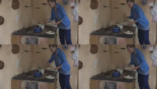 女人在厨房泥炉里用勺子从锅里拿食物。高清在线视频素材下载