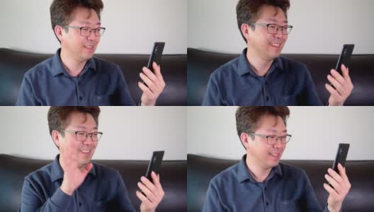 亚洲中年男子有一个愉快的视频通话使用智能手机。高清在线视频素材下载