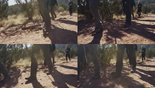 慢动作拍摄的一小群人的脚和远足杆，因为他们一起徒步在沙漠地形在一个阳光明媚的日子高清在线视频素材下载