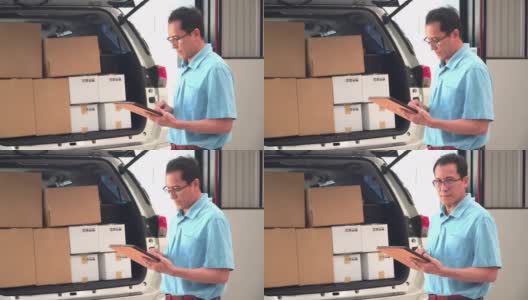 侧视图:中间人或邮政工作人员微笑着在平板电脑上检查包裹，以便与汽车一起在仓库里运送包裹。有积极情绪的邮政工作者的概念。高清在线视频素材下载