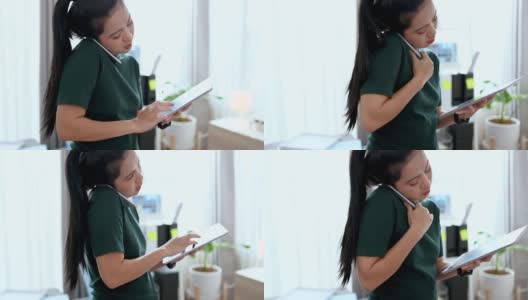 亚洲女建筑师在工作中使用平板电脑和手机，她站在家里工作。建筑师和工程师的概念。高清在线视频素材下载