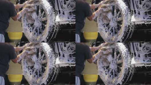 洗车和细化。一名专业工人正在洗车厂用肥皂泡沫洗车。汽车修理厂的工人正在清洗车轮高清在线视频素材下载