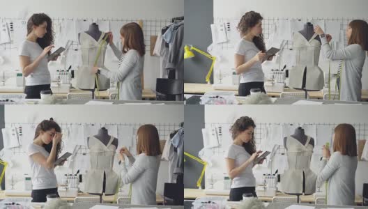 专业的女裁缝正在用卷尺在人体模型上测量图案，而她的同事正在用写字板写下测量数据。高清在线视频素材下载