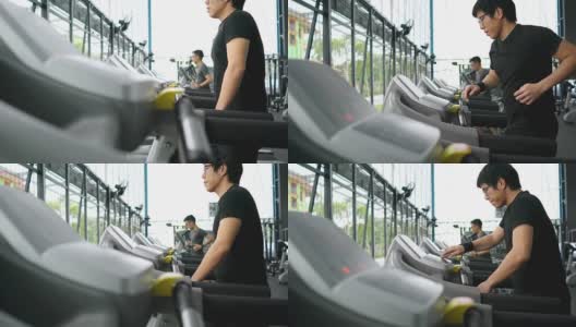 两个男人在跑步机上跑步，在健身房做有氧运动高清在线视频素材下载