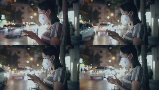 女人戴着口罩，在晚上使用智能手机来保护自己免受空气污染高清在线视频素材下载