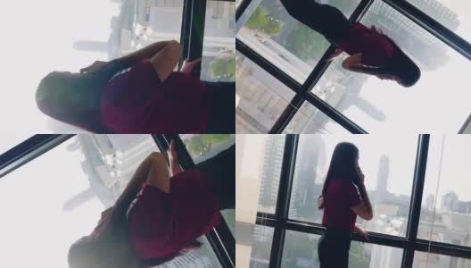 美丽的亚洲女性CEO在她的办公室用手机看窗外的大城市。高清在线视频素材下载