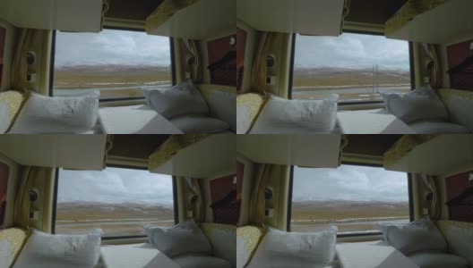 特写:从一辆卧铺火车的窗口拍摄的西藏平原风景。高清在线视频素材下载