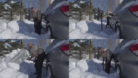 一个阳光明媚的冬日，一名50岁的白人男子在大雪过后，用铲子继续清理他停在车道上的汽车。高清在线视频素材下载