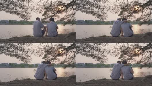 快乐的老夫妇坐在湖边的风景拥抱在树在傍晚日落。笑脸甜蜜的亚洲老年情人户外浪漫共享美好时刻。成熟的运动服装在公园锻炼高清在线视频素材下载