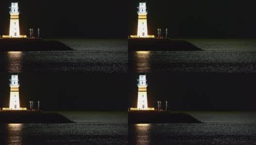 夜晚的灯塔，月光反射在海面上。高清在线视频素材下载