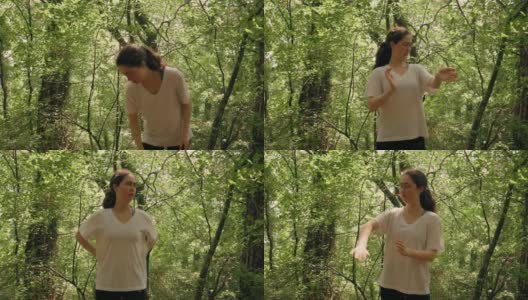 一名年轻女子挥手赶走蚊子，抓挠自己的蚊虫叮咬。背景是夏季森林。实时高清在线视频素材下载