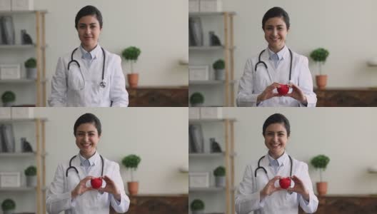 快乐年轻的印度裔女性心脏病学家向镜头展示心脏。高清在线视频素材下载