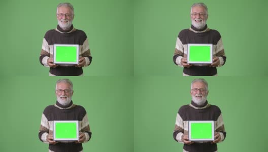 英俊的年长胡须男子穿着暖和的衣服，以绿色为背景高清在线视频素材下载