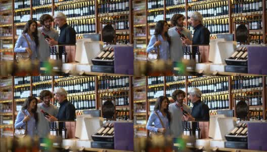 一对情侣在一家葡萄酒商店微笑着向酒庄老板询问葡萄酒的属性高清在线视频素材下载