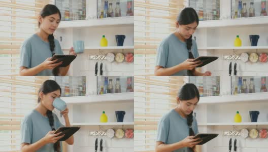 年轻美丽的亚洲女人在家里的厨房里一边喝着咖啡一边用着数字平板电脑，人和科技，Z一代的生活方式高清在线视频素材下载